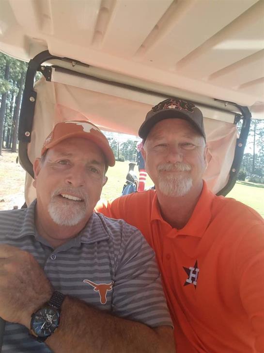 Two friends relax on a golf cart, smiling during a sunny day at a golf course.