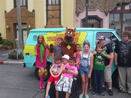 Children pose happily with a popular cartoon character at a theme park event.