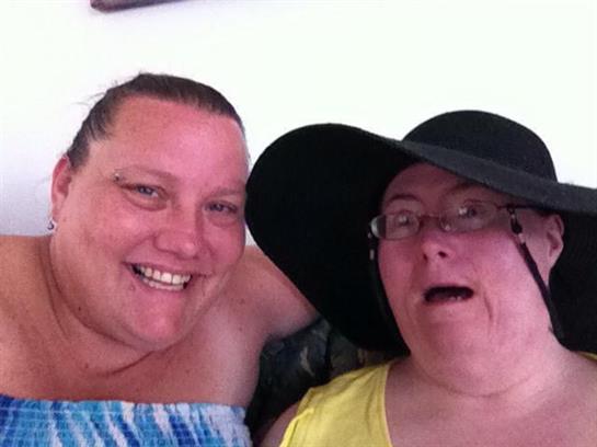 Two friends are smiling and enjoying each other's company in a casual indoor setting.