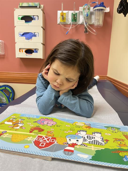 Young girl rests her chin on her hands, focused on a colorful puzzle while waiting.