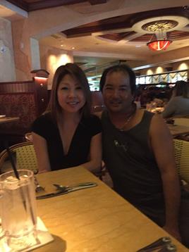 A couple sits together at a restaurant table, smiling and enjoying their meal in a warm atmosphere.