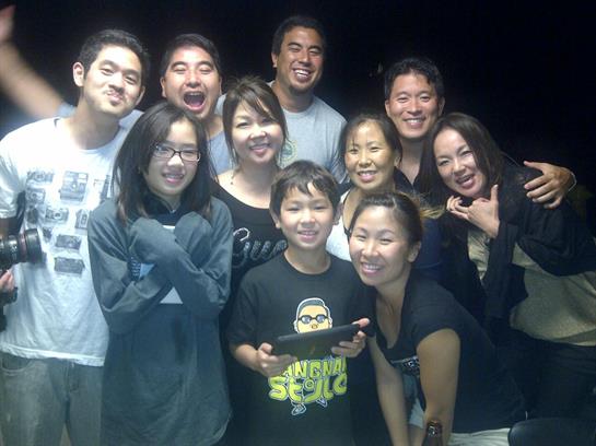 Group of friends smiling and posing together at a nighttime gathering indoors, sharing laughter.