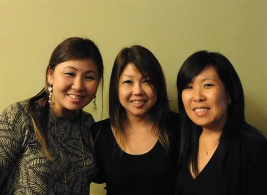 Three friends laugh and pose happily while enjoying a warm gathering in a relaxing atmosphere.