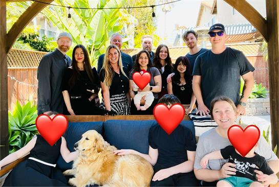 A diverse group of friends and family celebrate together in a backyard on a sunny day.