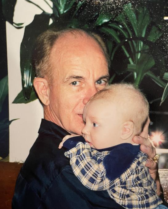 A loving moment captured of a grandfather joyfully holding his grandchild close indoors.