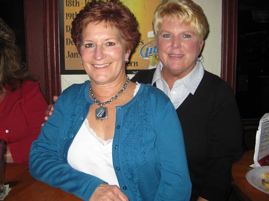 Friends share smiles and laughter while posing together in a lively bar atmosphere.