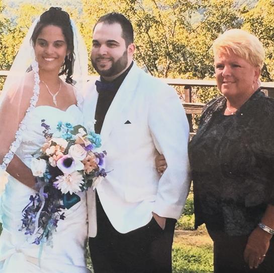 Bride and groom pose happily with a relative outdoors on their special day under the sun.