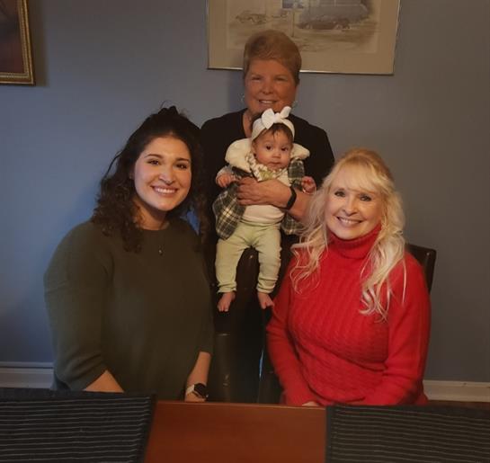 Four family members enjoy each other's company while smiling around a table.