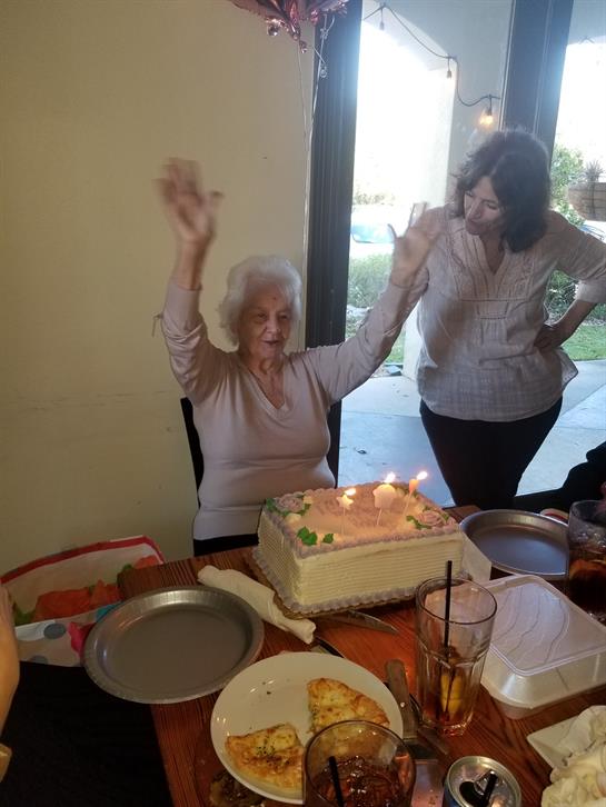 A woman raising her hands in front of a cake