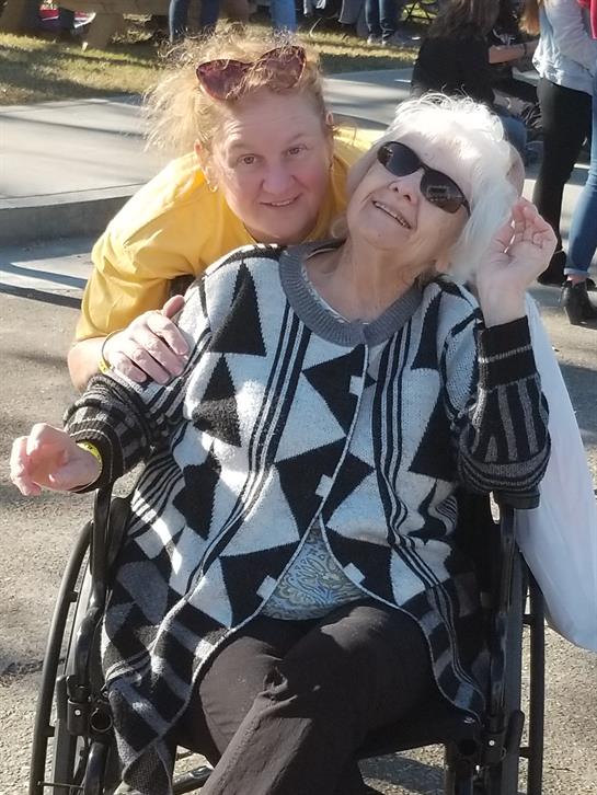 A woman sitting in a wheelchair with a woman in a yellow shirt