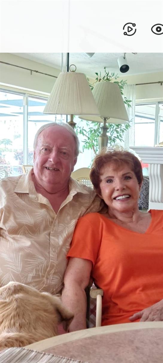 Happy elderly couple poses together in a cozy setting with natural light streaming in.