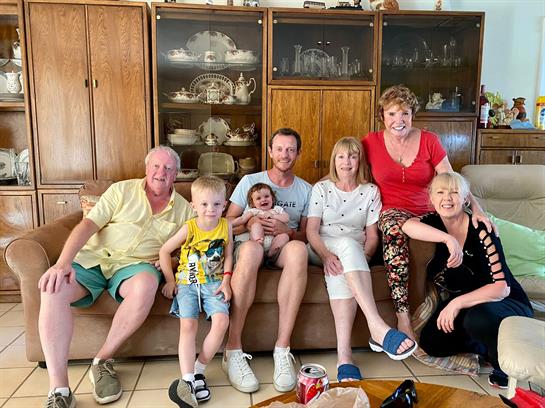 Seven family members share smiles and joy together on a cozy couch.