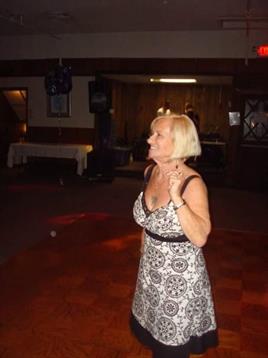 A joyful woman in a patterned dress enjoys dancing at a festive gathering.