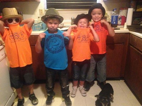 Four children showcase their fun outfits in a kitchen while enjoying a playful moment together.