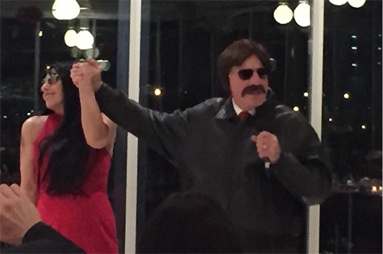 Two performers celebrate their performance by raising hands together in a well-lit venue.