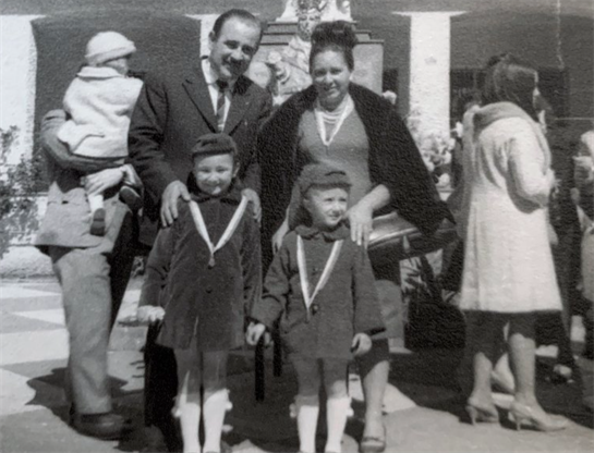 A family poses together outside during a public event, children wearing matching outfits.