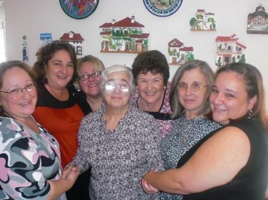 A group of seven women share laughter and memories while surrounded by cultural decorations.