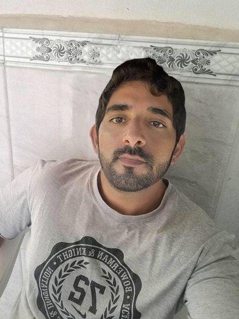 A person is sitting indoors, looking at the camera with a neutral expression on their face.