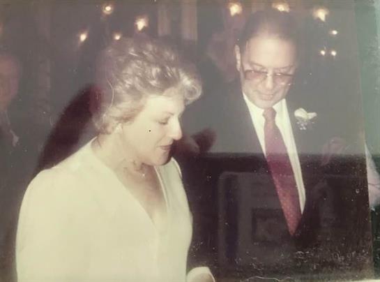 A couple shares an intimate moment at a wedding reception, surrounded by soft lighting and guests.