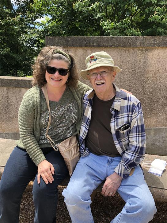 Two friends relaxed on a stone bench, smiling and enjoying the warm afternoon sun in the park.