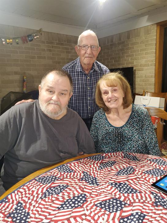 Three elderly friends cherish each other's company at a table dressed in red, white, and blue.