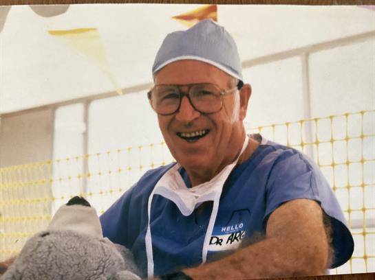 A cheerful veterinarian holds a stuffed animal while interacting with a patient in a clinic.