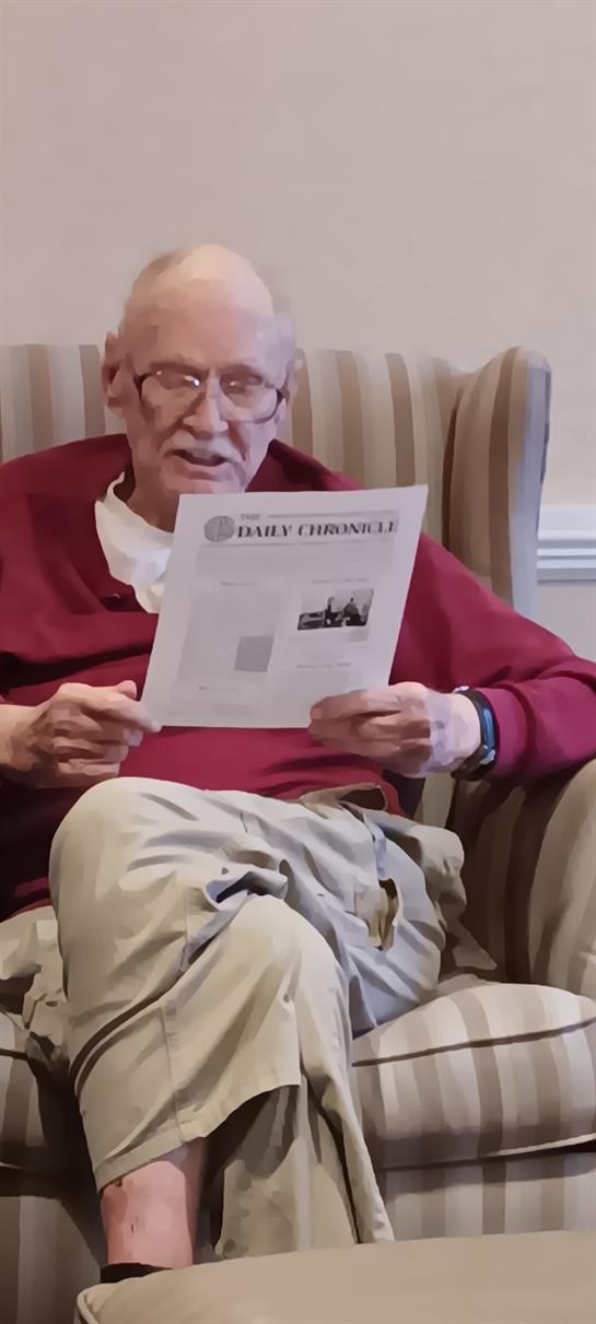 A man sitting in a chair reading a newspaper