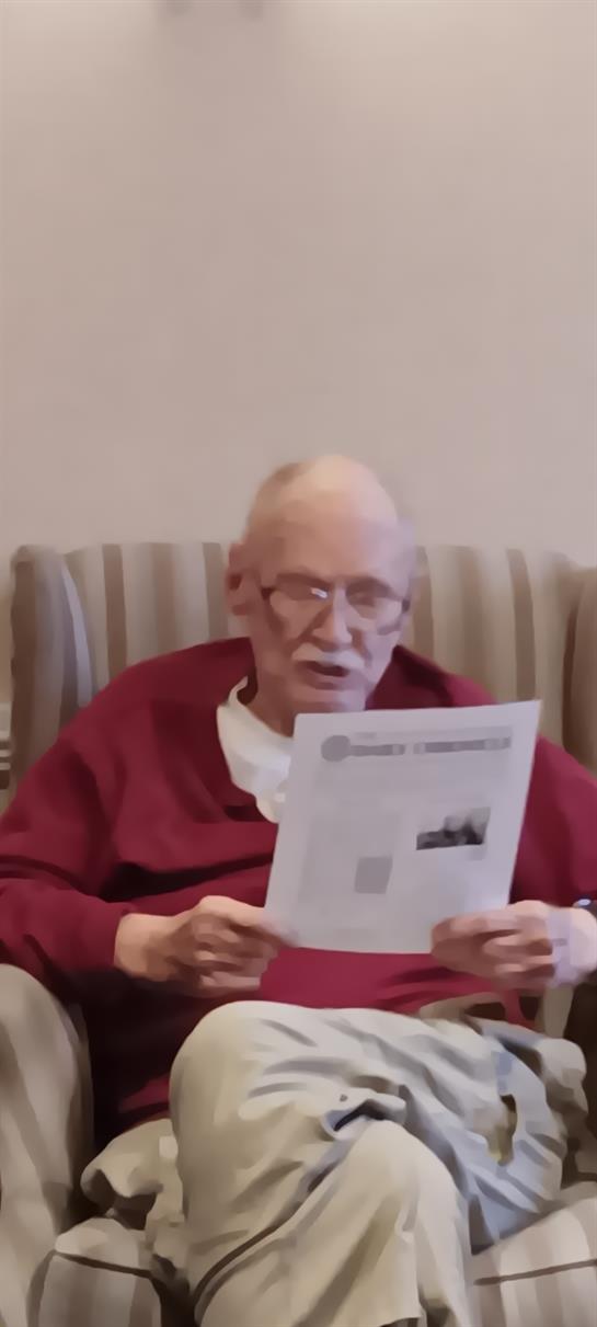 A man in a red sweater reading a paper
