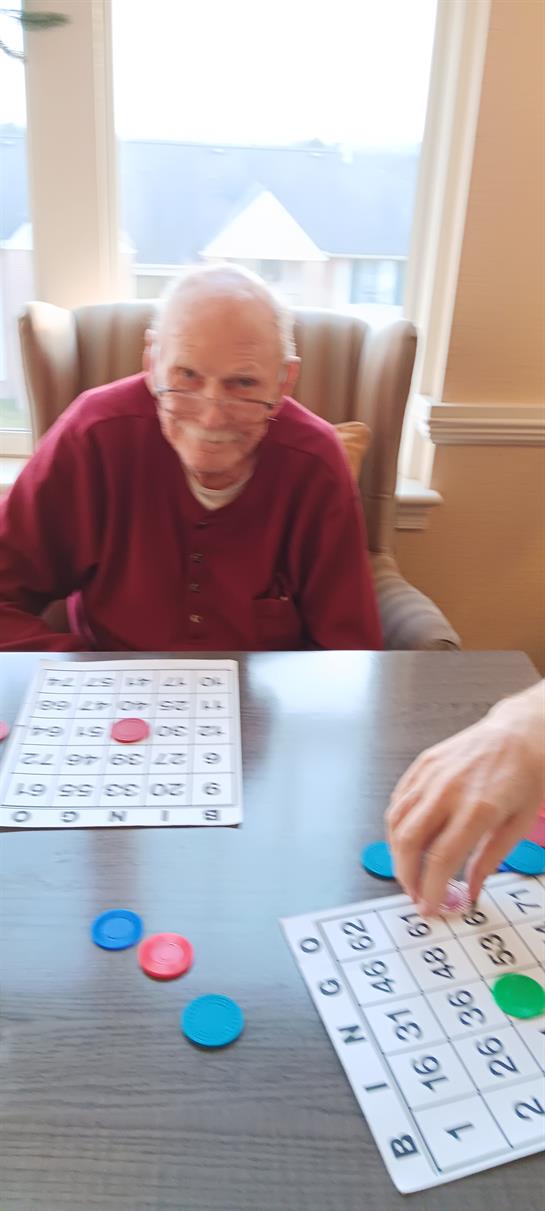 An old man sitting at a table playing a game