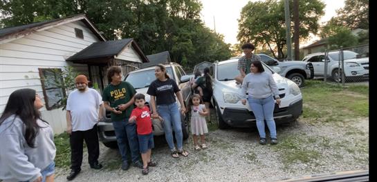 A family enjoys a cheerful gathering outside their homes as the sun sets.