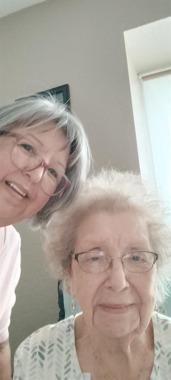 Two women share smiles at a family gathering in a bright, cheerful room.