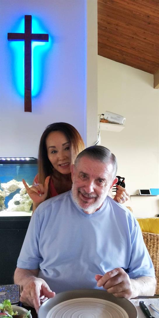 A man and woman share a happy moment indoors surrounded by warm decor and a glowing cross.