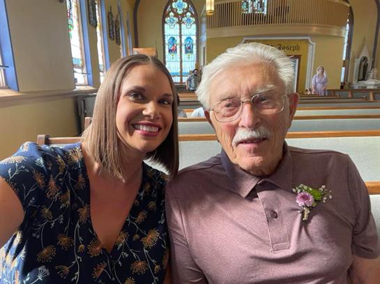 Two smiling individuals posing together in a church setting, surrounded by beautiful architecture.