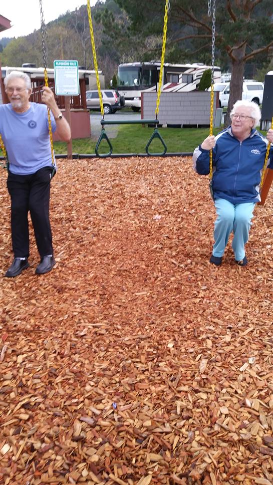 Seniors share joy on swings at a park, creating happy memories in a sunny afternoon.