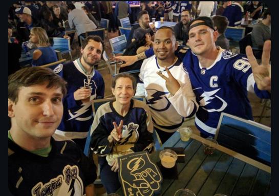 Group of friends enjoying drinks and cheering for their team at a vibrant sports bar.