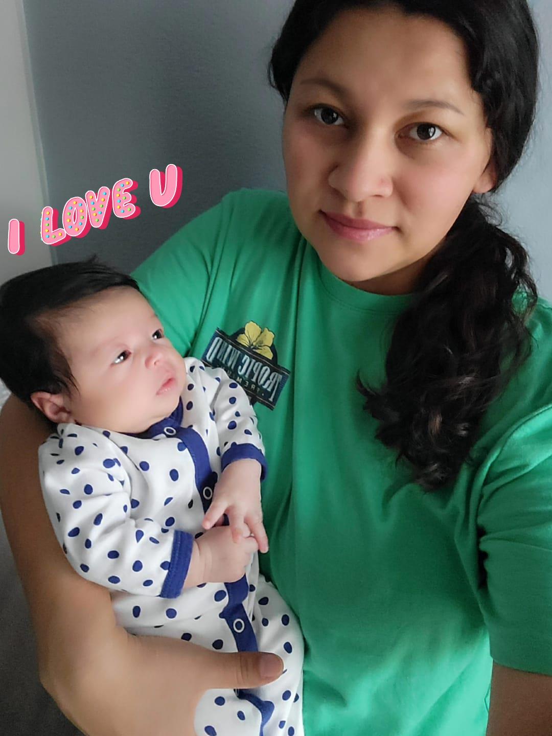 A mother cradles her baby in a loving embrace, reflecting warmth and affection indoors.