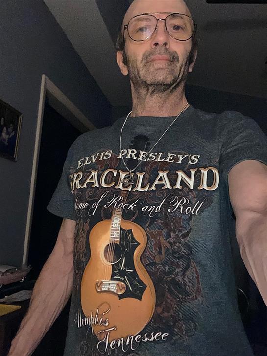 Individual poses with a musical instrument, showcasing their appreciation for Elvis's legacy.