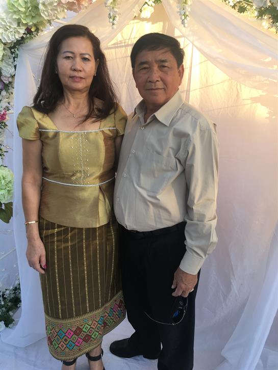 A couple dressed in traditional costumes poses together in a beautifully decorated setting.
