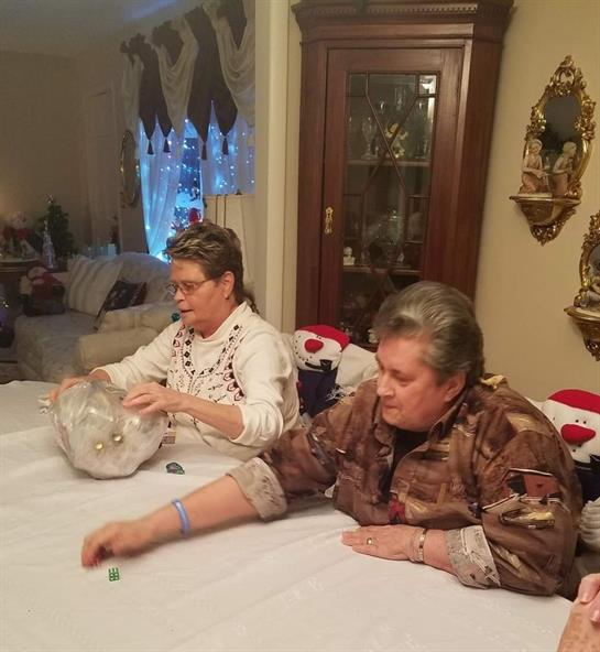 Two friends engage in a relaxing activity at a dining table decorated for winter festivities.