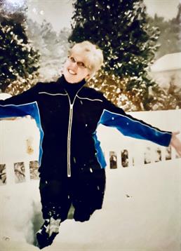 A person enjoys a playful moment in the snow, smiling while surrounded by winter scenery.
