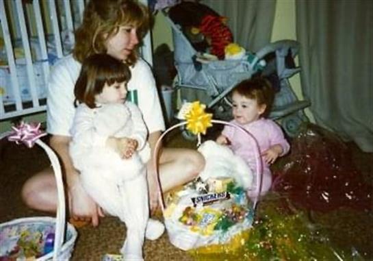 Two young children interact with dolls and colorful Easter baskets in a warm room.