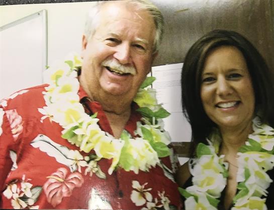 Two individuals are enjoying a joyful celebration wearing bright floral leis and smiles.