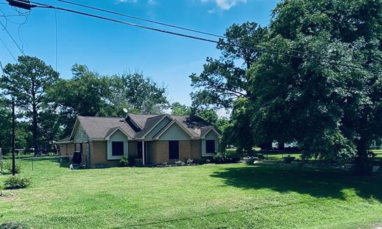 A charming house sits in a spacious yard under blue skies with scattered clouds.