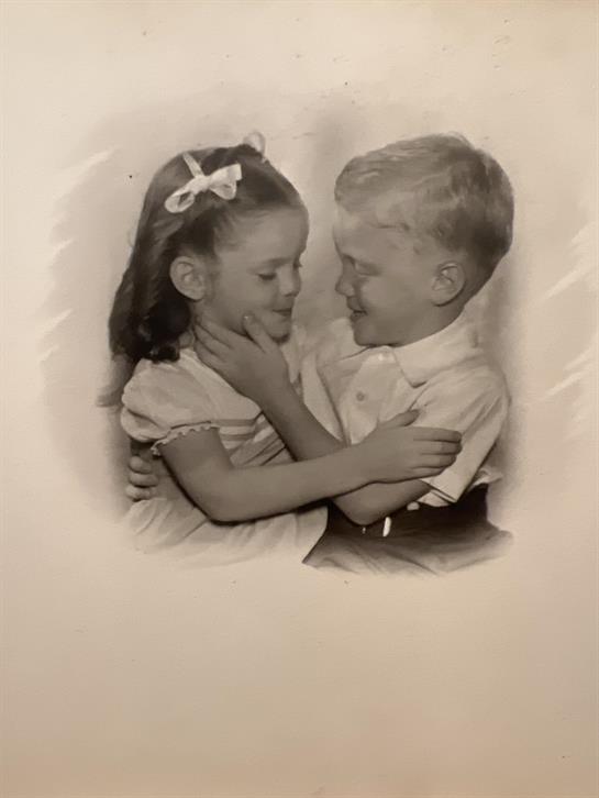 Two children share a playful embrace, smiling and enjoying their time together outdoors.