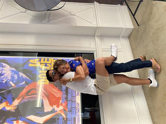 A man lifts a woman playfully in a colorful urban space, showcasing joy and connection.