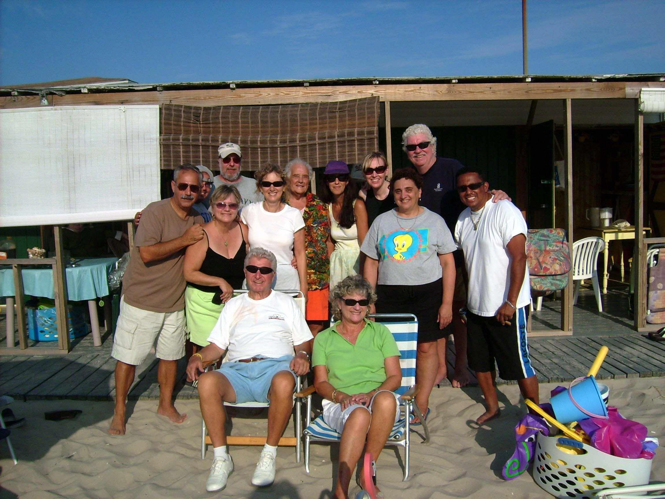 Friends and family gather on the beach, relaxed and cheerful, enjoying a sunny summer day.