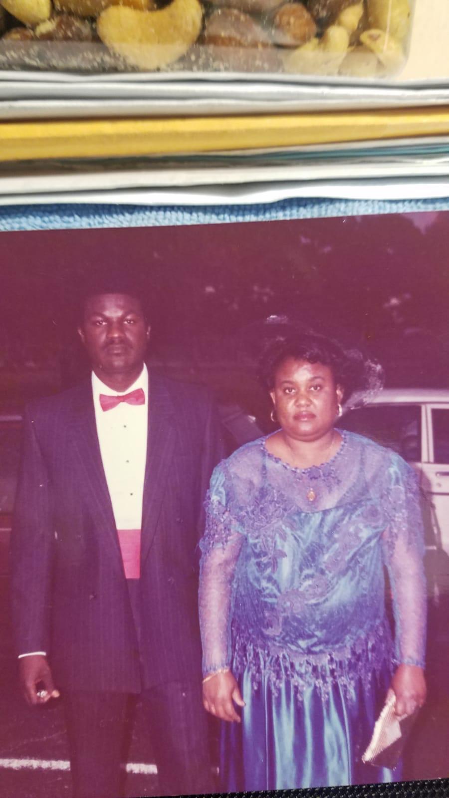 A couple stands side by side, dressed elegantly for a special evening event outdoors.