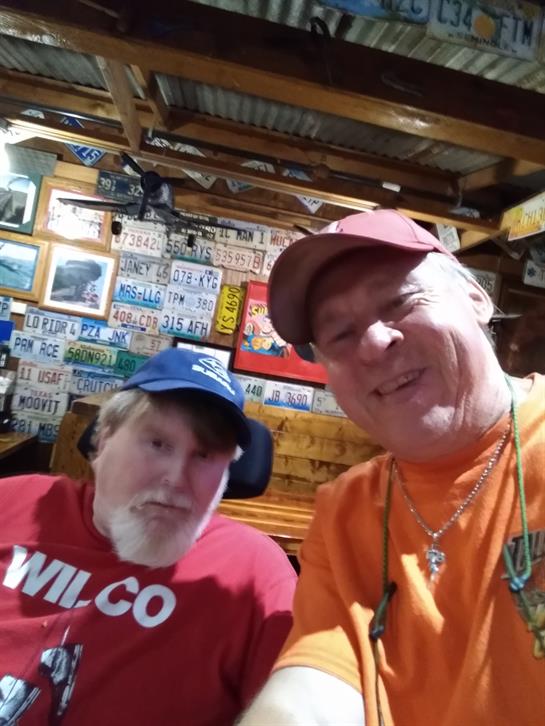 Friends enjoy a casual moment together in a rustic bar adorned with memorabilia.