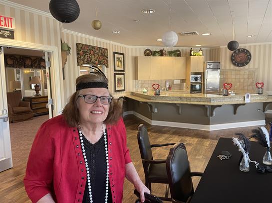 A woman in vintage attire enjoys a lively gathering in a decorated room with elegant decor.