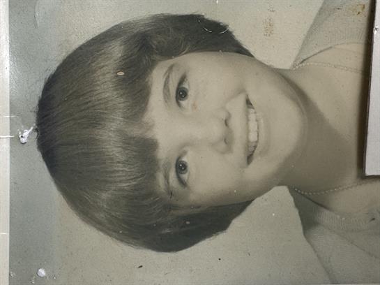 A young girl with a short hairstyle and a cheerful expression poses for a portrait.